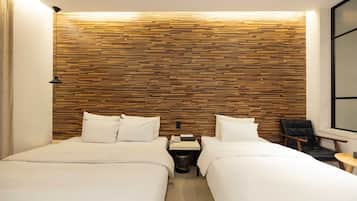 A hotel room with two beds, a wooden wall panel, a small bedside table with a phone, and a chair by the window.