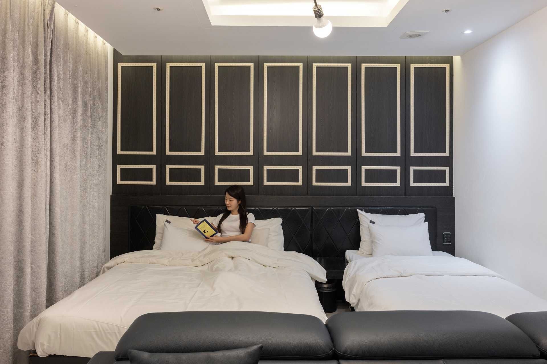 Un dormitorio moderno con una cama grande, dos camas más pequeñas y un diseño de cabecera único.