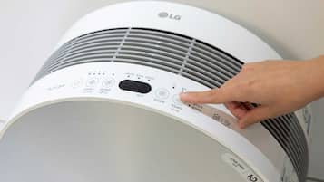 A white LG air conditioner with a control panel featuring multiple buttons and a digital display.