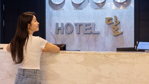 A hotel reception desk with clocks displaying Sydney, Seoul, London, and New York times.