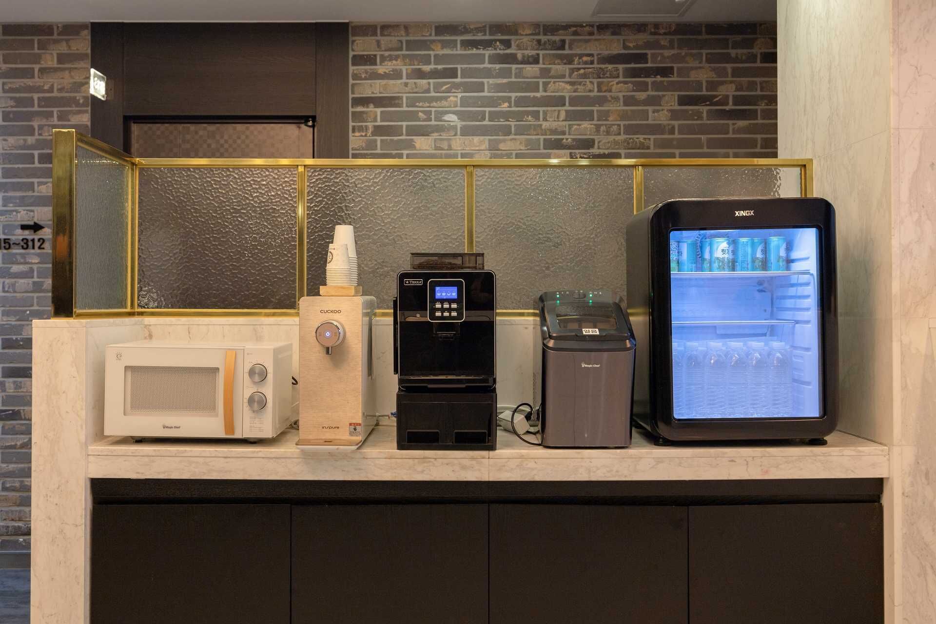 A kitchenette with a microwave, a coffee machine, a water dispenser, and a refrigerator.