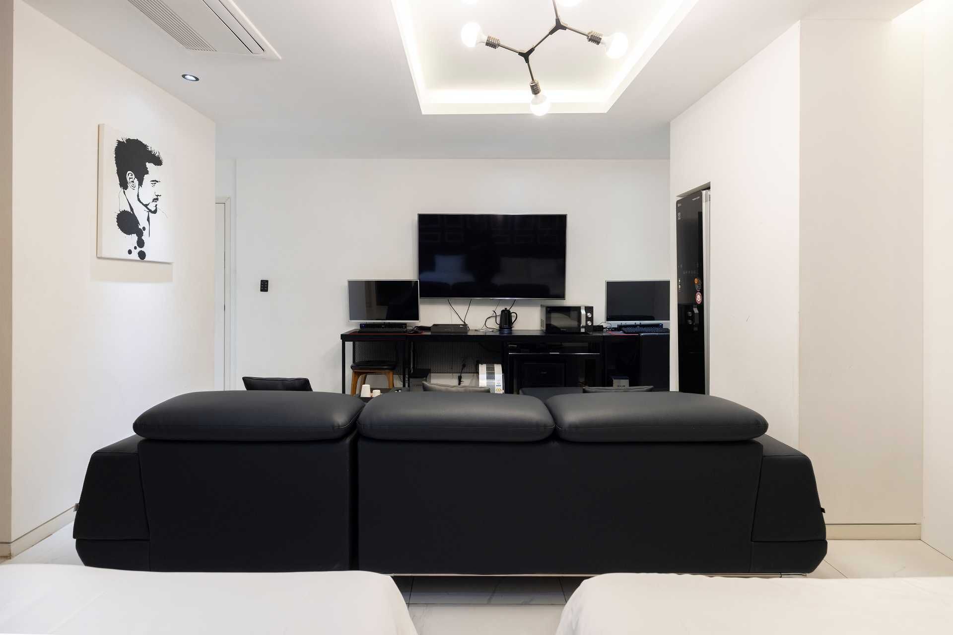 A modern living room with a black sofa, a flat-screen TV, and a coffee table.