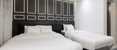 Una habitación de hotel moderna con dos camas, un cabecero oscuro con diseños geométricos y un tragaluz arriba.