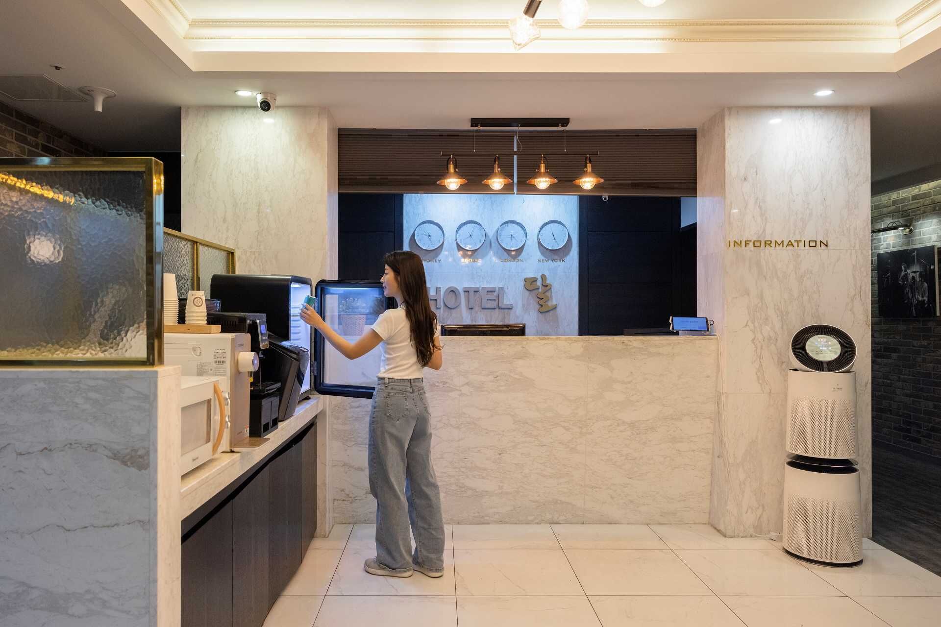 A hotel reception area with a digital kiosk, a clock displaying multiple time zones, and a sign indicating 'INFORMATION'.