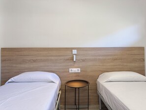 A hotel room with two single beds, a small round table, and a wooden headboard. - Agi Rescator 222 Apartamento for rent in Roses Girona. (Rosas / Roses)