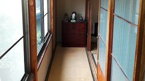 Un estrecho pasillo con suelo de esteras de tatami, puertas correderas de madera y un farolillo japonés tradicional colgando del techo.