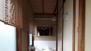 Un pasillo estrecho con suelo de madera, una ventana con persianas, un lavabo y un armario.