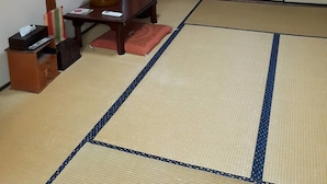 Una habitación japonesa tradicional con suelo de tatami, una mesa baja con un hervidor y una puerta corredera.