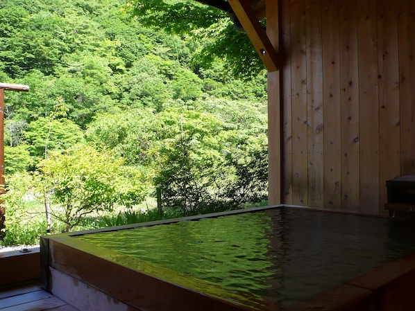 Eine Holzhütte mit Whirlpool und Blick auf einen üppigen Wald.