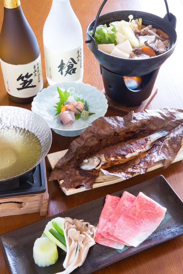 A variety of Japanese dishes including a pot of soup, a bottle of sake, and a plate of sashimi. - Houzansou Bekkan (Takayama)