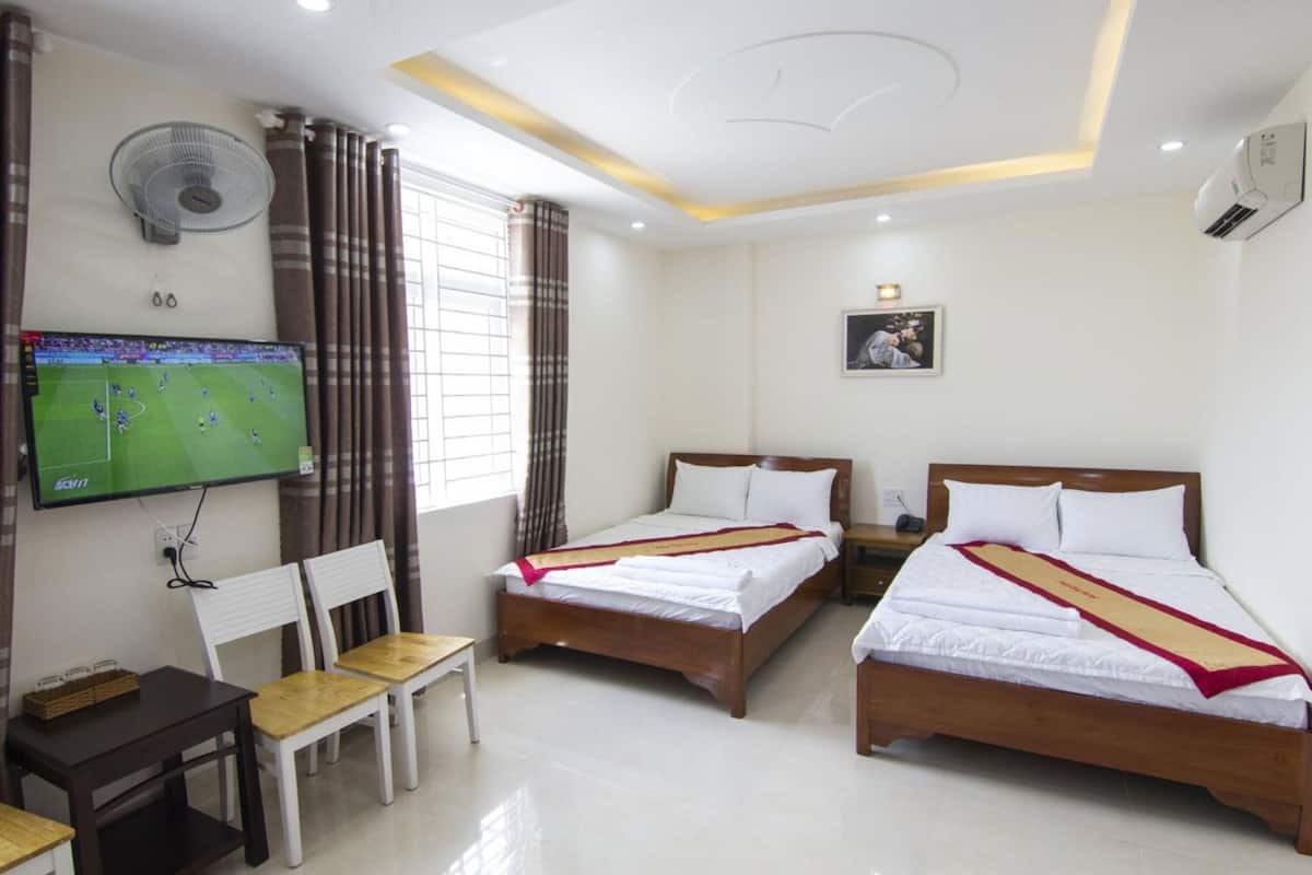 A hotel room with two beds, a TV, a desk, and a chair.