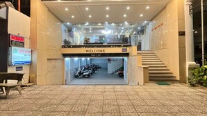 L’entrée de l’hôtel BIÊN NGÔC est marquée par une pancarte « BIENVENUE », elle comprend un espace abrité où sont garées des motos, et son sol est décoré de motifs.