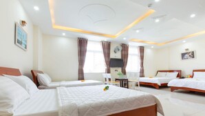Une chambre d’hôtel avec trois lits, un bureau et une chaise.