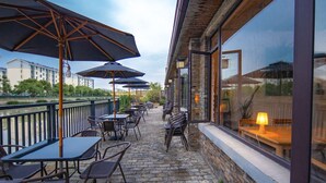 An outdoor patio with tables and chairs, umbrellas, and a view of a river and buildings. - Shanghai Linxi Hotel-Free shuttle bus to Pudong Airport and Disneyland (Shanghai)