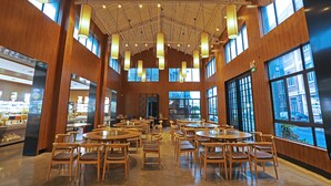 A spacious indoor area with multiple round tables and chairs, large windows, and hanging light fixtures. - Shanghai Linxi Hotel-Free shuttle bus to Pudong Airport and Disneyland (Shanghai)