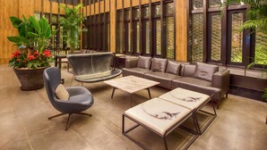 A modern lounge area with leather furniture, a large potted plant, and a view through large windows. - Shanghai Linxi Hotel-Free shuttle bus to Pudong Airport and Disneyland (Shanghai)