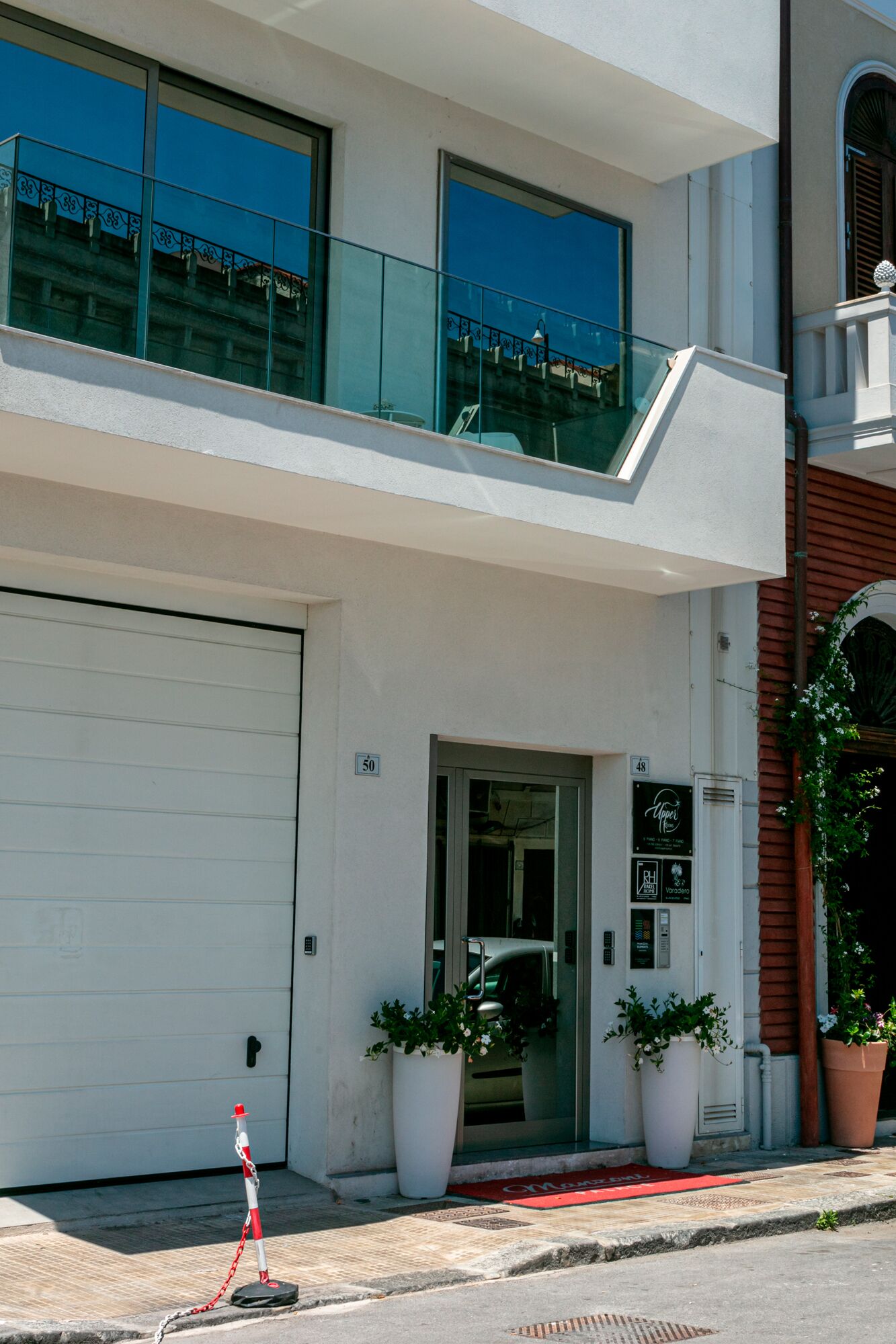 En moderne bygning i to etager med en hvid facade, store vinduer og en glasbalkon.