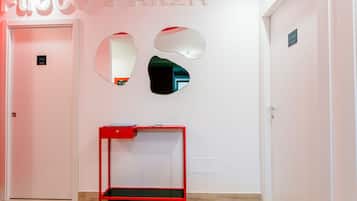 Un pasillo con un escritorio rojo, una puerta con un letrero que dice 'MARE' y una pared con los letreros 'EUROCO & ARIA' y 'NATURA'.