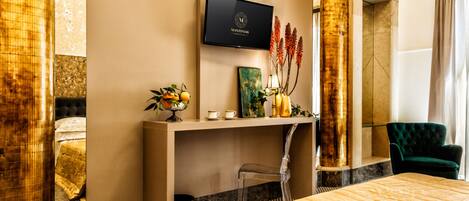 Ein Hotelzimmer mit Bett, Schreibtisch mit Fernseher, Stuhl und Blumen in einer Vase.