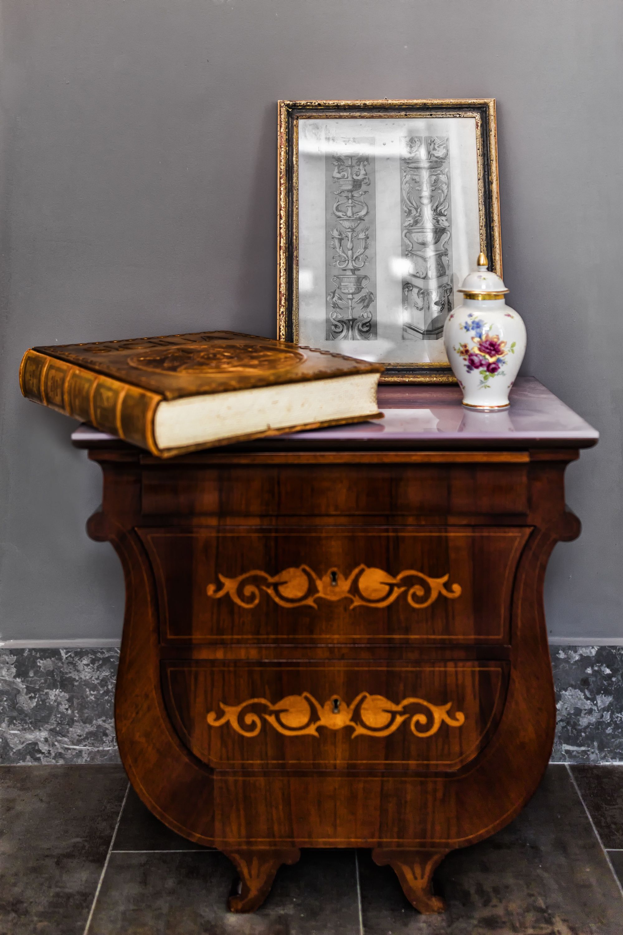 Um armário de madeira com um livro e um quadro em cima.