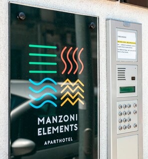 A manzoni elements apartment hotel entrance with a keypad and a glass door displaying the logo. - Manzoni46 (Milazzo)