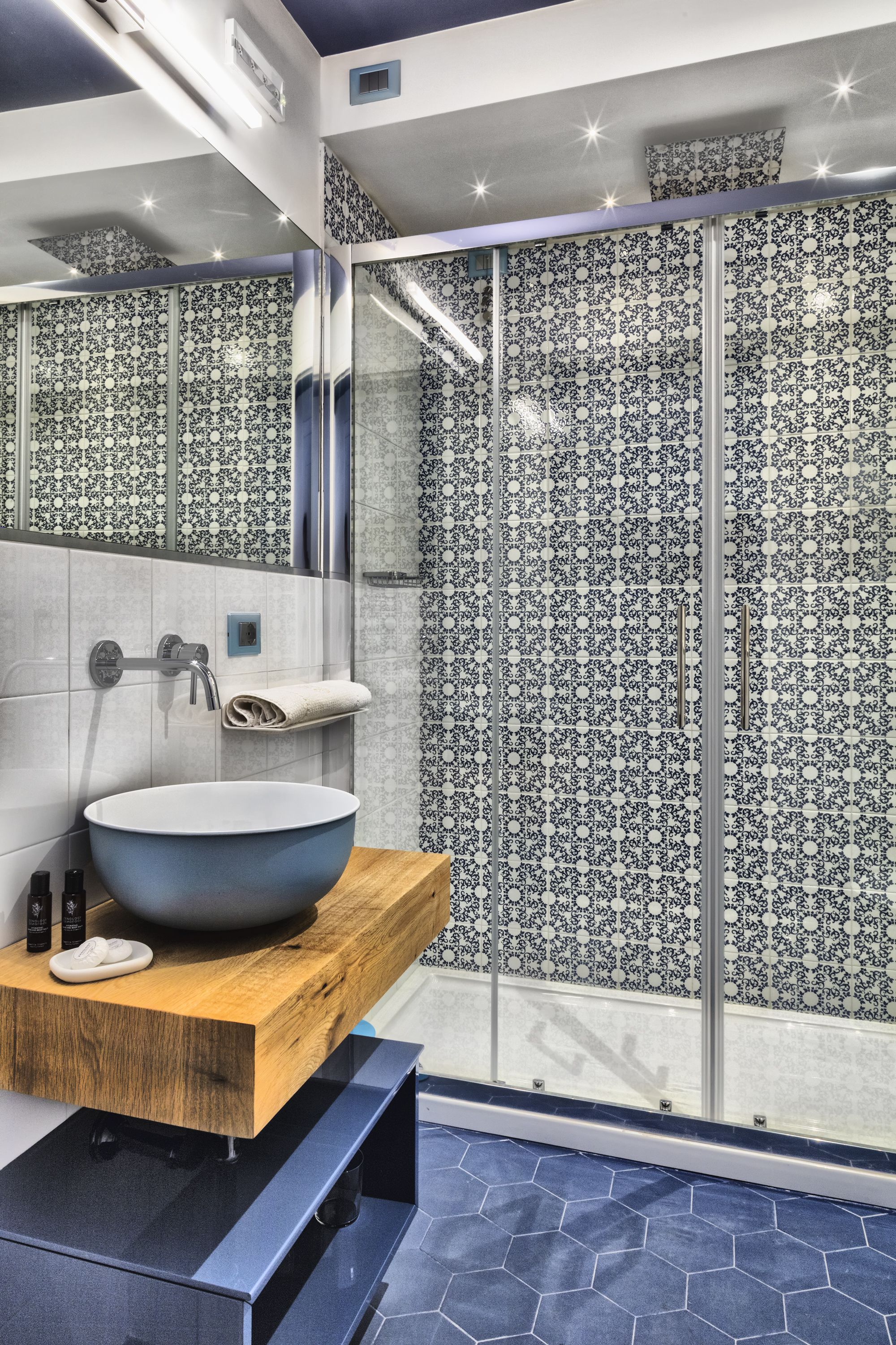 Un bagno moderno con un lavabo a incasso di grandi dimensioni, un piano in legno e piastrelle decorate.