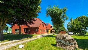 Ein rotes Backsteinhaus mit einem gepflasterten Auffahrt und einem Steinschild.