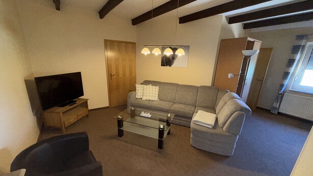 Ein Wohnzimmer mit Fernseher, Sofa und Couchtisch.