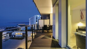 A modern hotel balcony with a view of the sea and a distant ship.