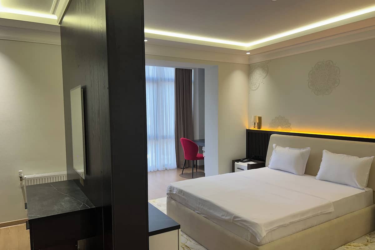 Habitación de hotel con cama, escritorio, silla y mesita de noche.