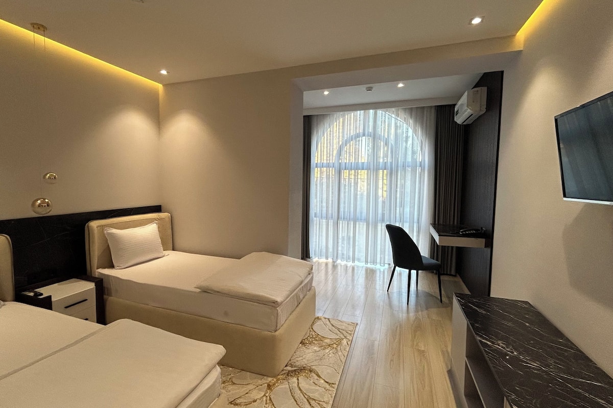 Una habitación de hotel moderna con dos camas, un escritorio, una silla y una televisión.