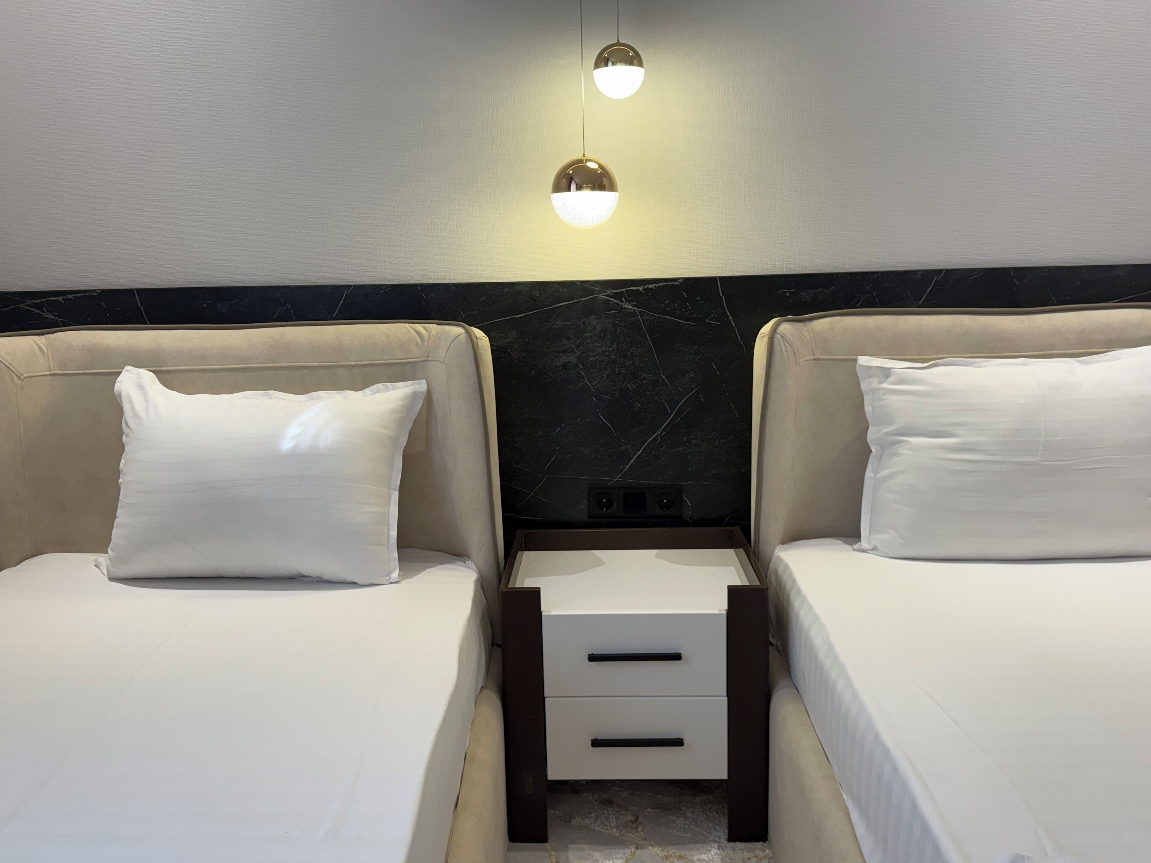 Une chambre d’hôtel avec deux lits, chacun étant équipé d’un oreiller et d’une table de chevet avec des tiroirs.