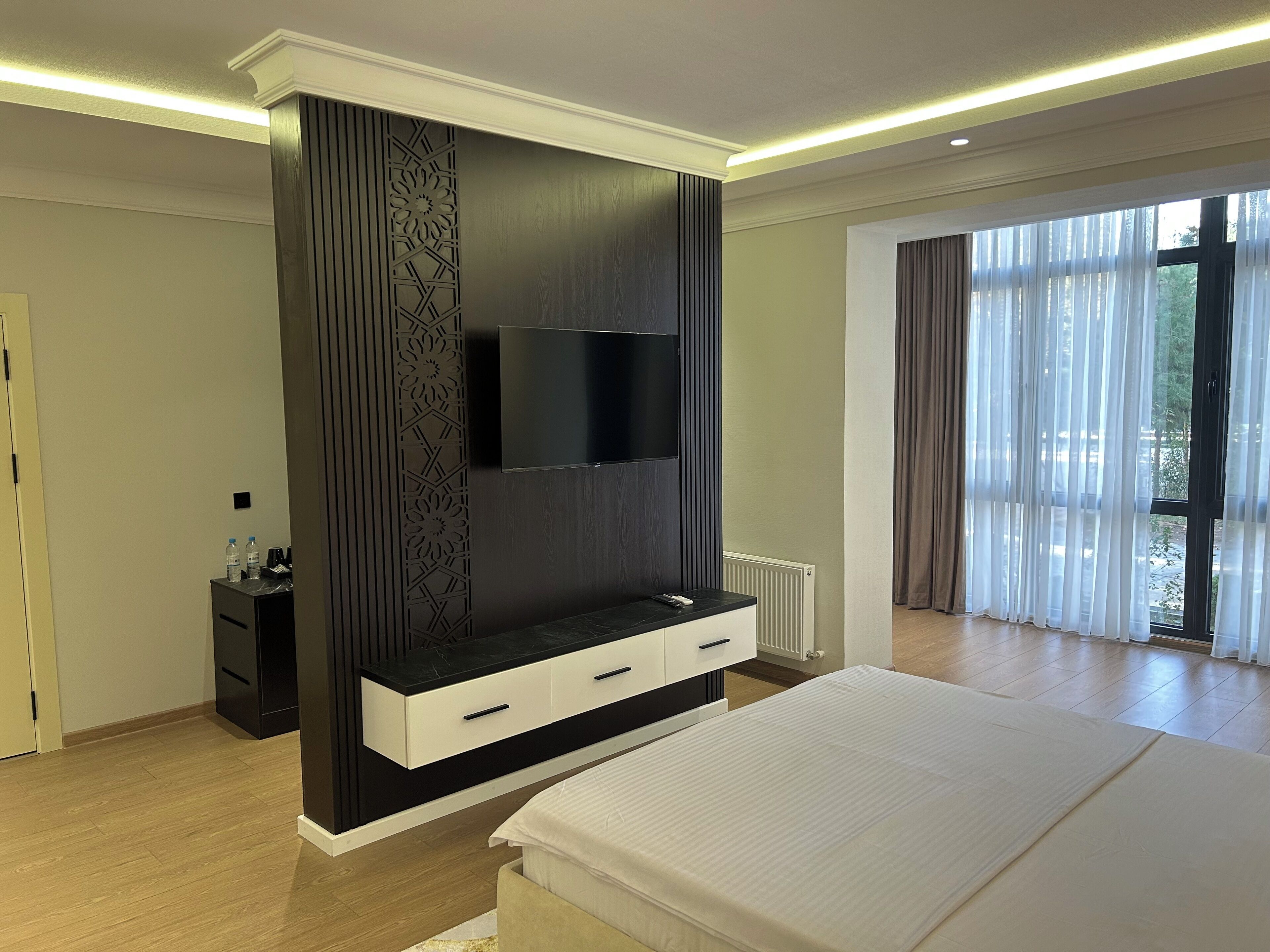 A modern bedroom with a large bed, a built-in TV, and a minimalist design.