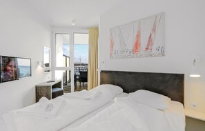 Ein Hotelzimmer mit Bett, Schreibtisch, Stuhl, Fernseher und einem Gemälde.