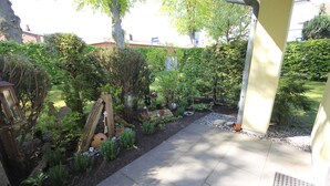 A garden with a paved pathway, wooden structures, and various plants. - At Schmiedestraße, Sonneneck - At Schmiedestraße, Sonneneck (Wustrow)