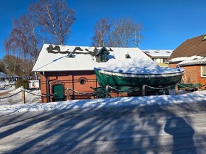 Um edifício de tijolos com um barco verde em exposição, rodeado por neve.