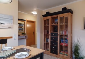 Ein Essbereich mit einem Holztisch, gedeckt für zwei Personen, einem Schrank mit Glastüren und einem Bild an der Wand.