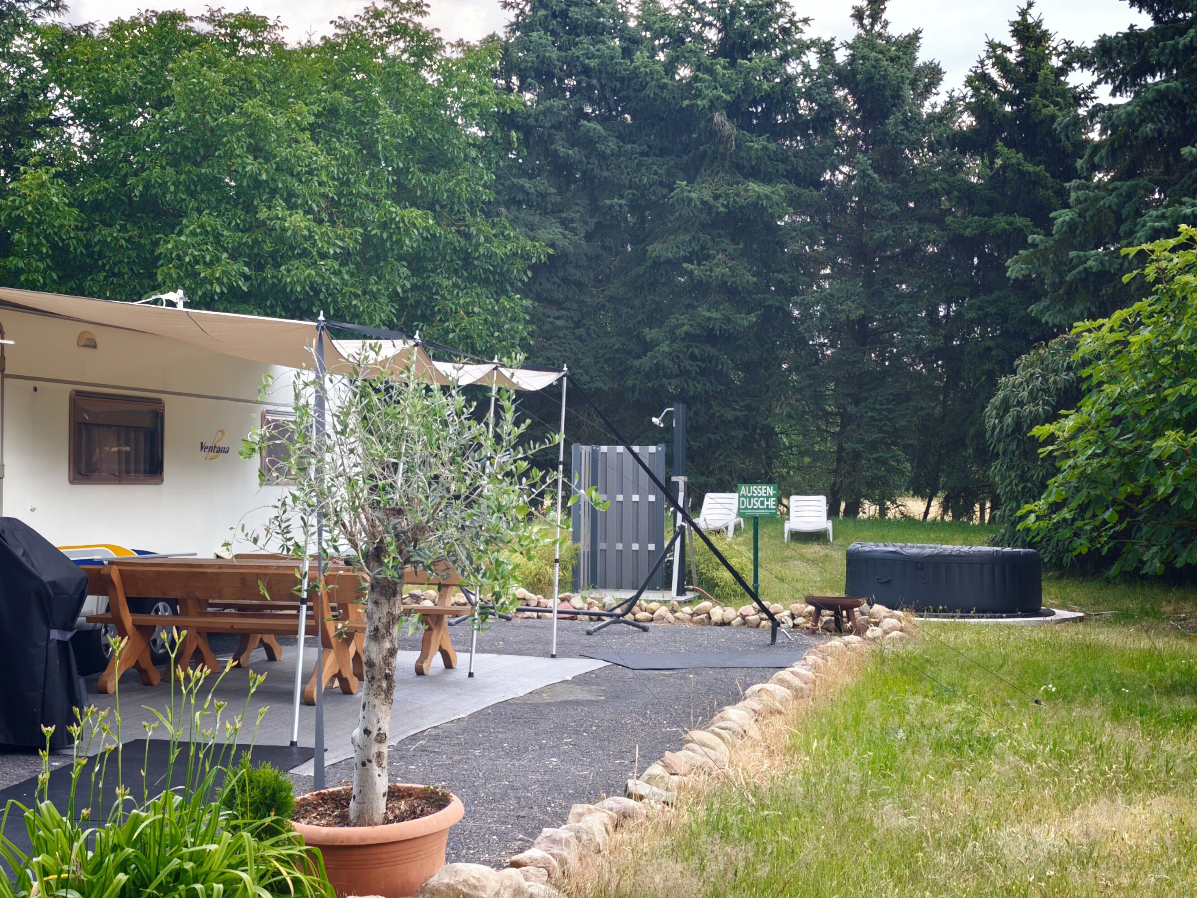 A campsite with a tent labeled 'Ventana,' a small tree, outdoor seating, and a grill area.