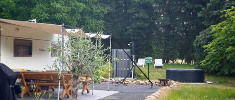 A campsite with a tent labeled 'Ventana,' a small tree, outdoor seating, and a grill area.