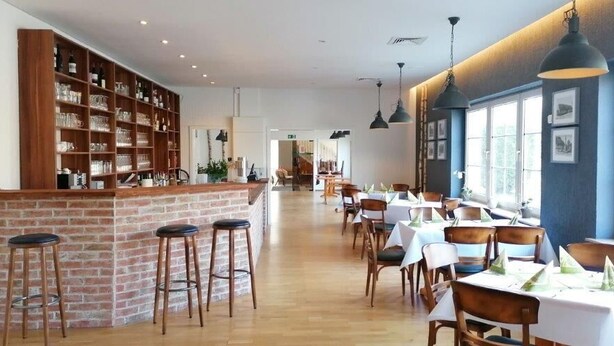 A restaurant with a brick bar area, wooden chairs, and tables set for dining. - Craft Berry GmbH Hotel and Restaurant at the Milestone (Jerichow)
