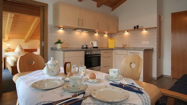 Una cocina acogedora con armarios de madera, una mesa de comedor dispuesta para el desayuno y un horno a la vista.