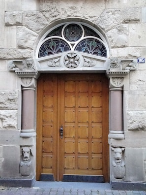 Un edificio de piedra con una puerta de madera grande, una ventana ornamentada y estatuas de leones.