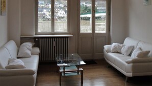 A living room with two white sofas, a glass coffee table, and a chandelier.