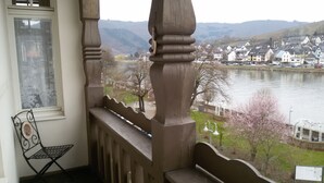 A balcony with a view of a lake, houses, and a chair.