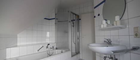 Un baño con bañera, ducha, lavamanos y espejo.