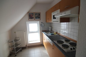 Una cocina con estufa, lavamanos y ventana.