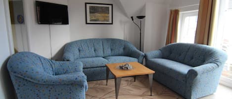 A living room with two sofas, a coffee table, a flat-screen TV, and a floor lamp.