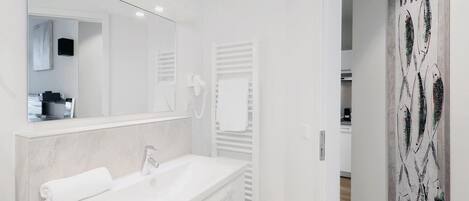 A modern bathroom with a white vanity, a large mirror, and a towel rack.