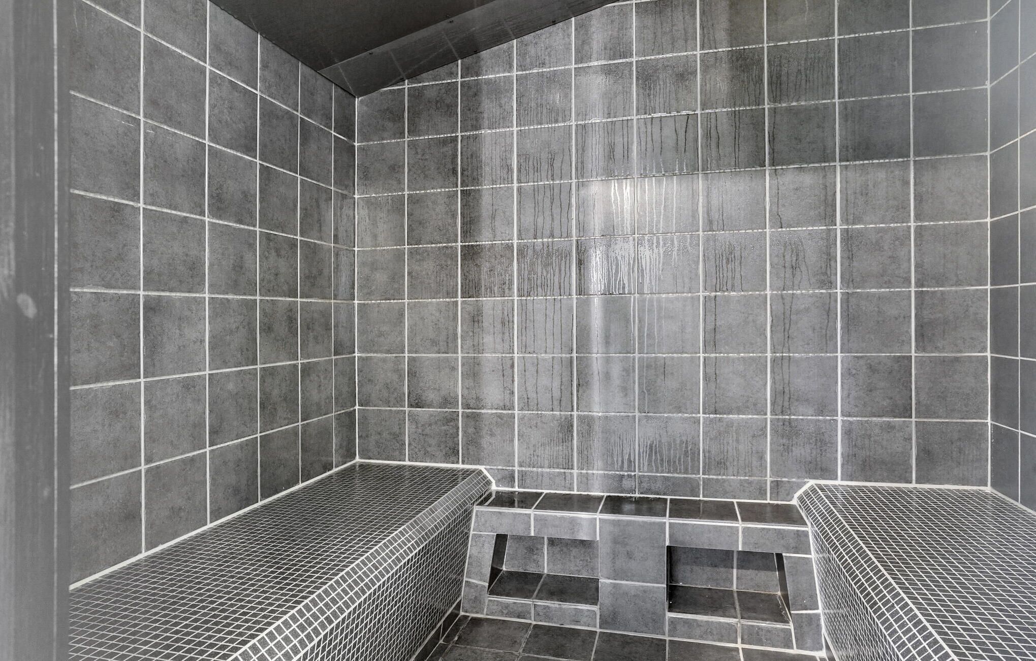 A tiled shower area with a grid pattern and a small bench.