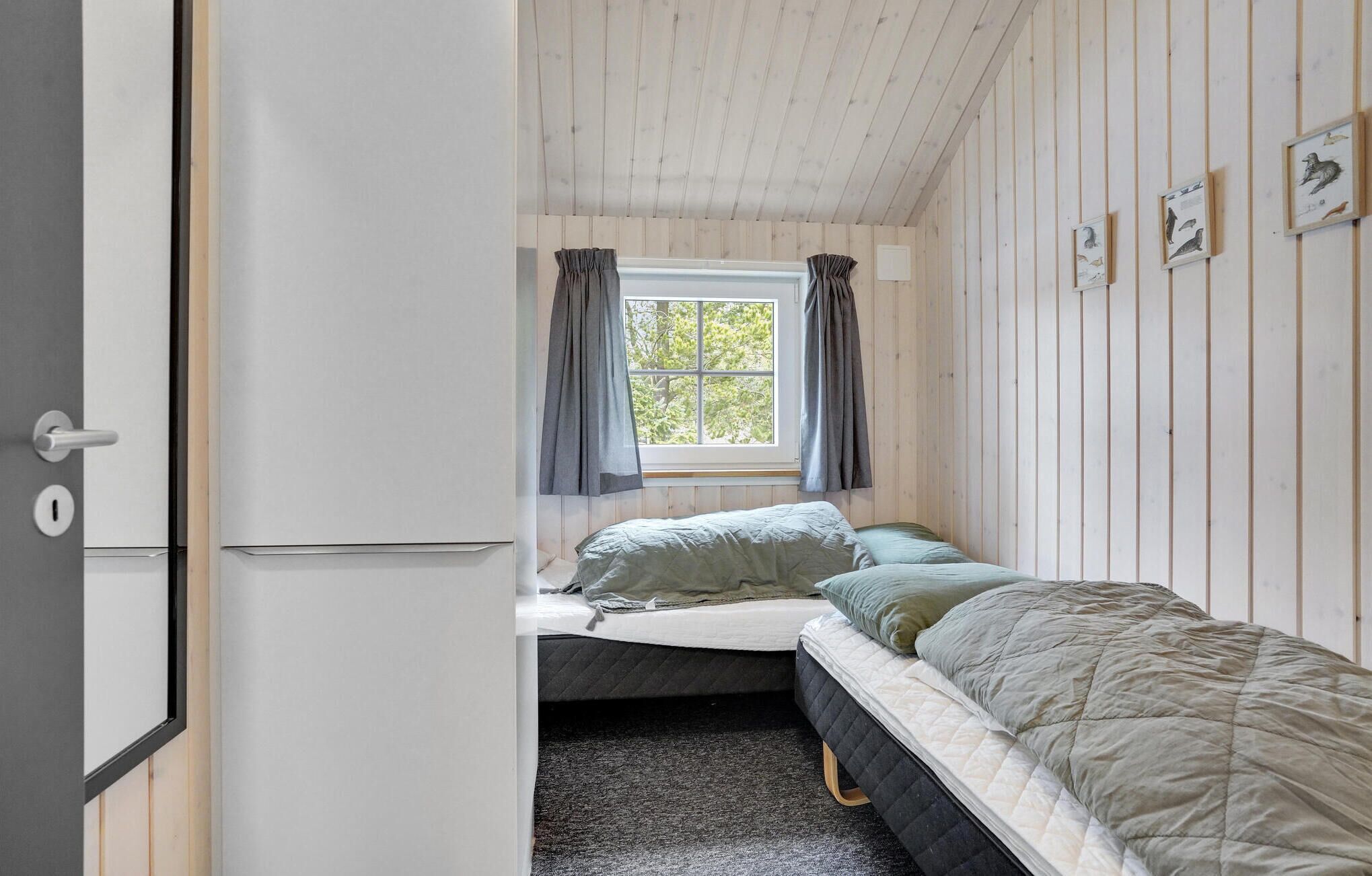 A compact bedroom with a single bed, a window with curtains, and a door.